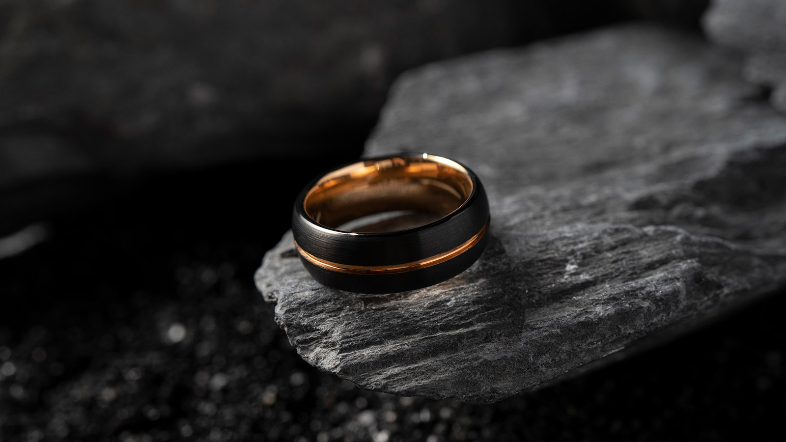 The black tungsten ring, with a dark gold setting in the middle, was placed on the stone
