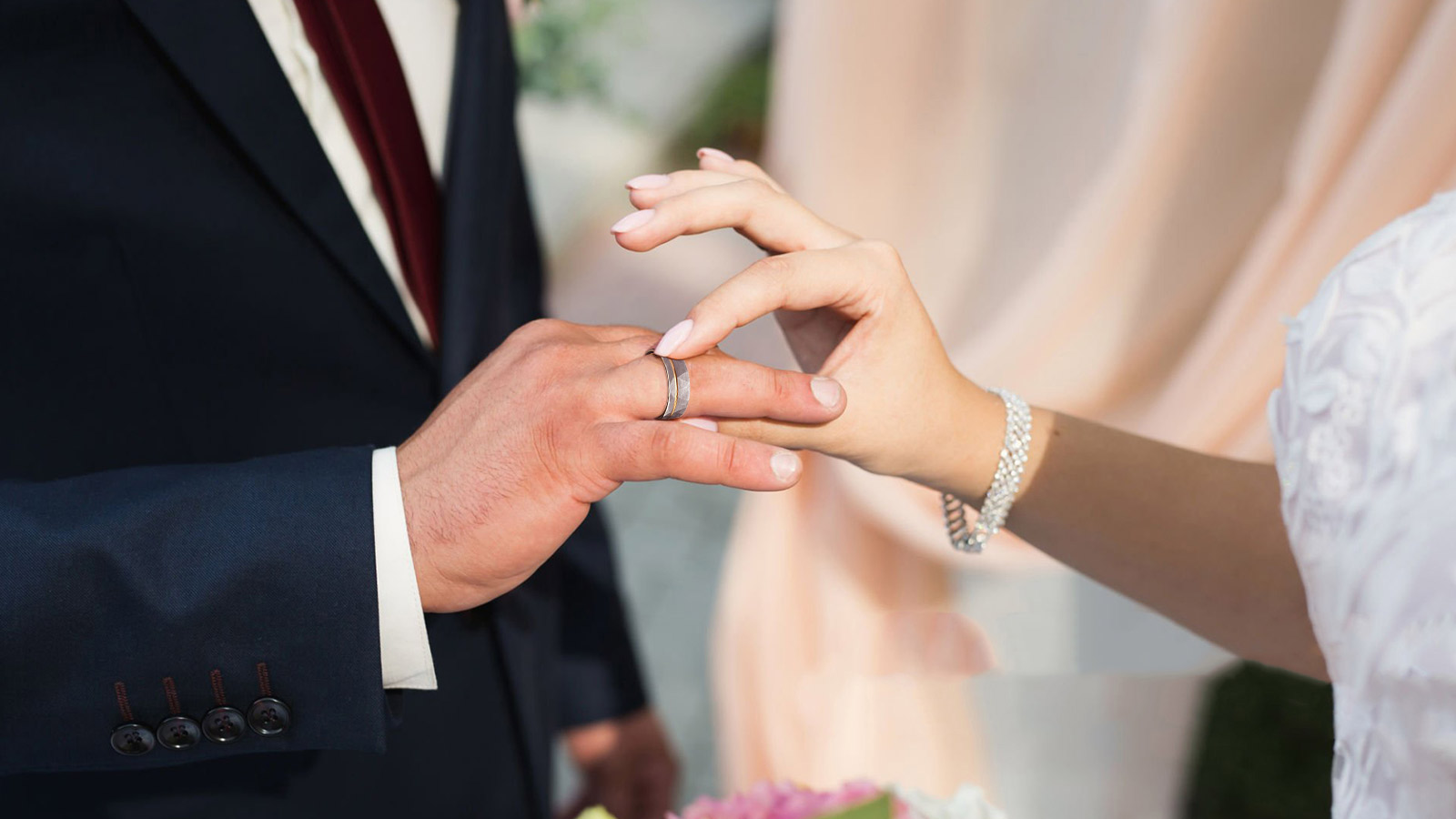 The couple at the wedding are putting wedding rings on each other